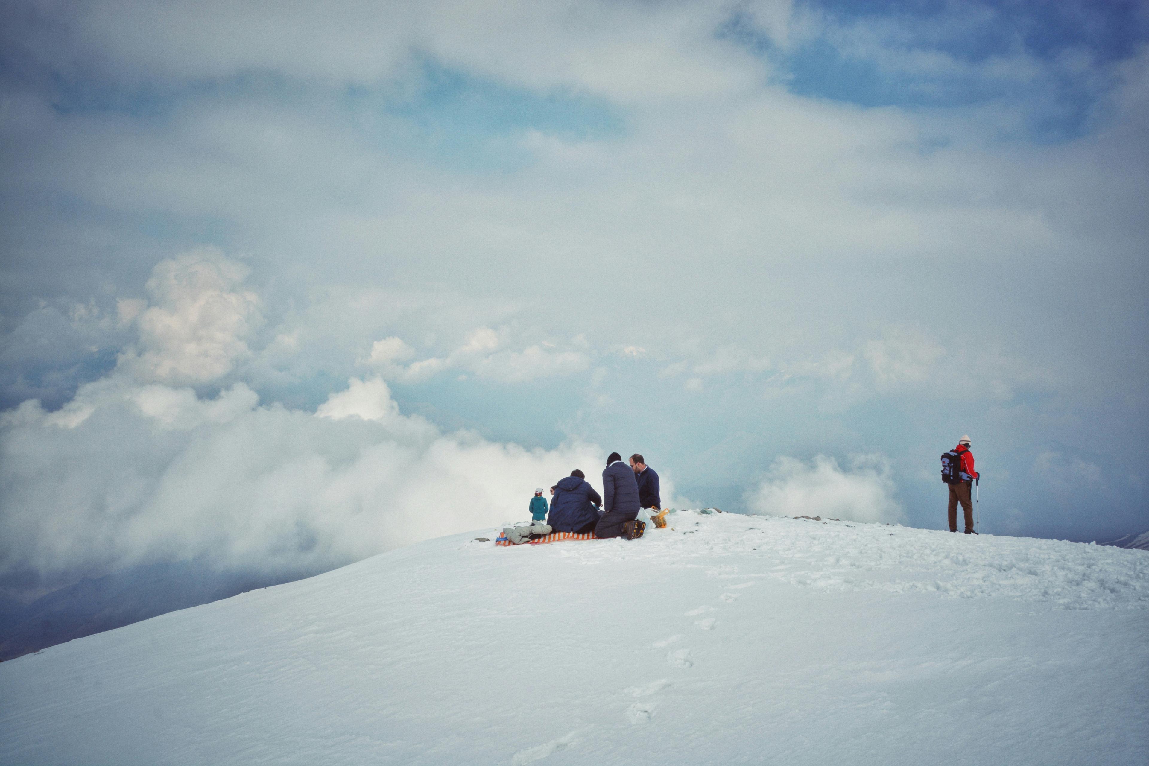 Persone sulla neve sopra un mare di nuvole
