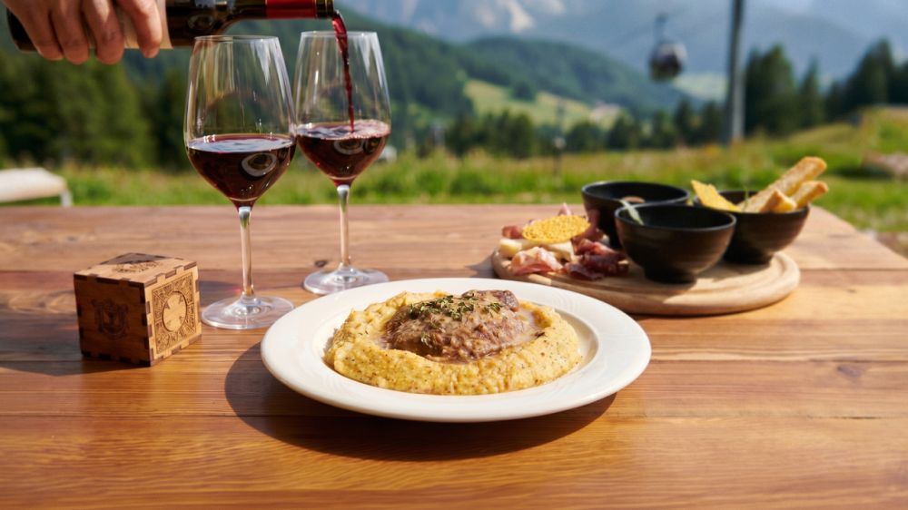 Polenta, vino e tagliere serviti con vista sulle montagne